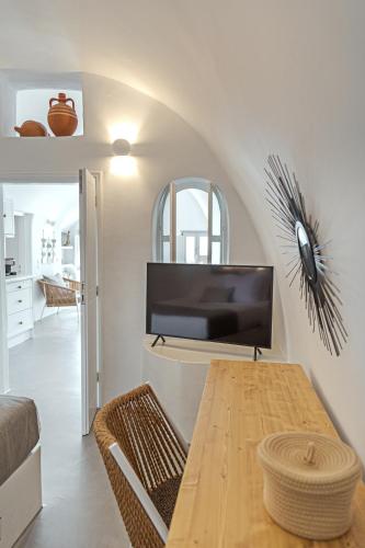 a living room with a table and a tv at Helianthus Dream Homes in Oia