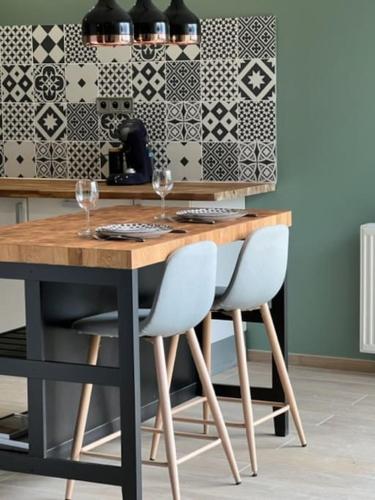 - une table à manger avec 2 chaises et des verres à vin dans l'établissement Maison Les Géraniums, à Mers-les-Bains