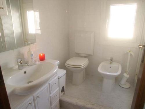 ein weißes Bad mit einem WC und einem Waschbecken in der Unterkunft Calle Burchio in Grado