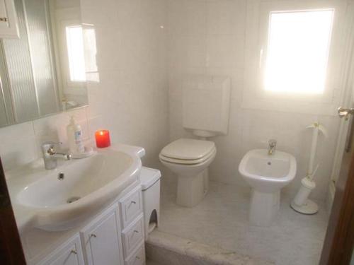 a white bathroom with a toilet and a sink at Calle Burchio in Grado