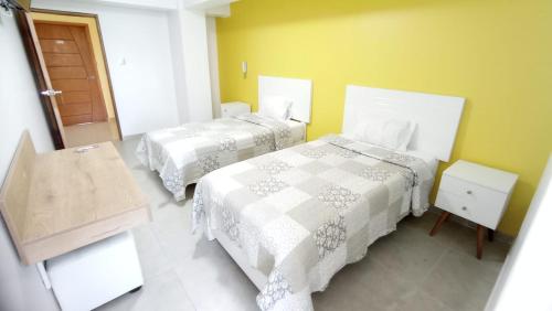 2 Betten in einem Zimmer mit gelben Wänden in der Unterkunft Hotel Santa Maria in Ica