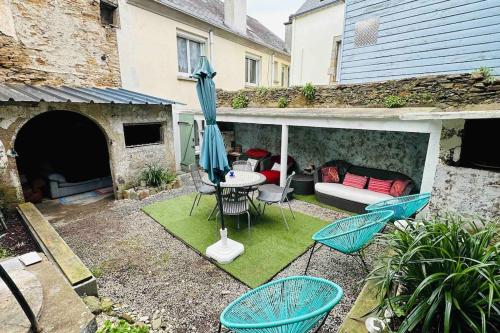 eine Terrasse mit einem Tisch, Stühlen und einem Sonnenschirm in der Unterkunft Appartement Jardin du Palais- Relaxation Centrale in Le Palais