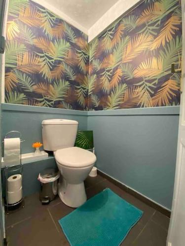 a bathroom with a toilet and a blue wall at Appartement Jardin du Palais- Relaxation Centrale in Le Palais