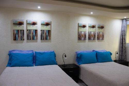 2 Betten in einem Zimmer mit Gemälden an der Wand in der Unterkunft Casa Irma in Guatemala