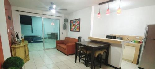 a kitchen and living room with a couch and a table at Casa de playa Herradura con piscina y jacuzzi in Puntarenas