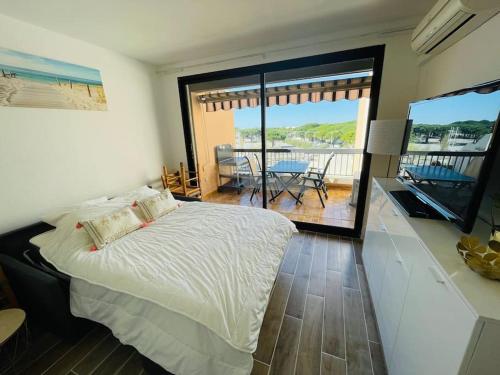 - une chambre avec un lit et un balcon avec une table dans l'établissement Studio à 350m de la plage, terrasse ouverte, clim, au Grau-du-Roi