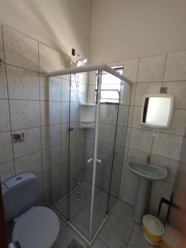 uma casa de banho com um chuveiro, um WC e um lavatório. em Residencial Medeiros em Guarda do Embaú