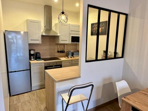 a kitchen with a refrigerator and a table with a chair at Appartement à 15min de paris in Drancy