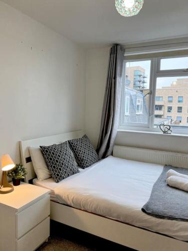 een kleine slaapkamer met een bed en een raam bij New build 2 bed flat, London in Londen