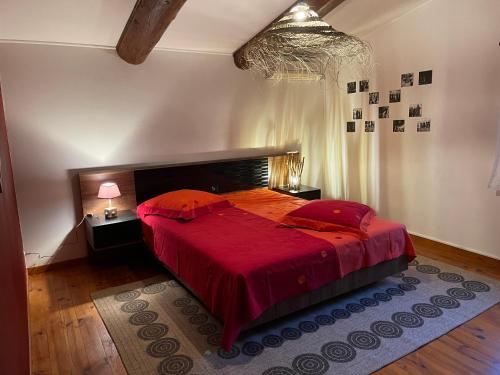 a bedroom with a large bed with a red bedspread at MAS D’OLIVE ET KALOU in Sauve