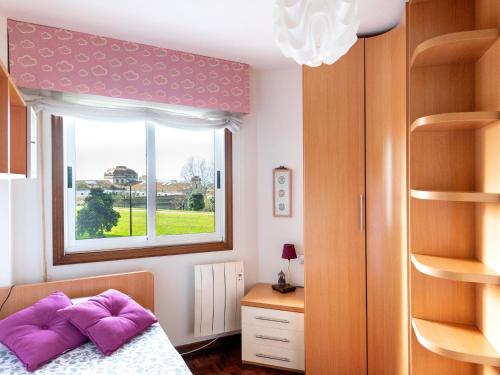 Un dormitorio con una cama con almohadas moradas y una ventana en APARTAMENTO TORRE DE HÉRCULES A CORUÑA con GARAJE, en A Coruña