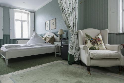 a bedroom with a bed and a chair and a window at Hotel Zum Alten Brunnen in Rheine