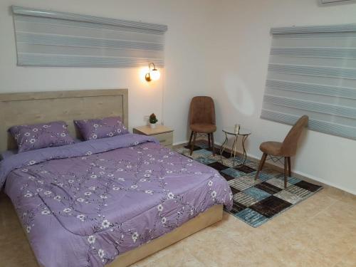 a bedroom with a purple bed and two chairs at גבעת האלון in Ein Kinya