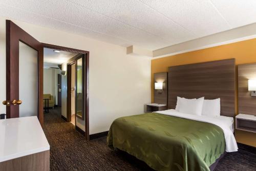 ein Hotelzimmer mit einem Bett und einem Spiegel in der Unterkunft Quality Suites Milwaukee Airport in Milwaukee