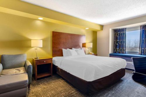 a hotel room with a bed and a chair at Clarion Pointe Staunton East in Staunton