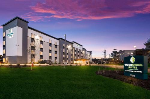 a building with a sign in front of a grass field at WoodSpring Suites Knoxville - Cedar Bluff in Knoxville