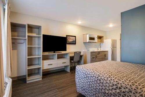 a bedroom with a bed and a desk with a television at WoodSpring Suites Knoxville - Cedar Bluff in Knoxville