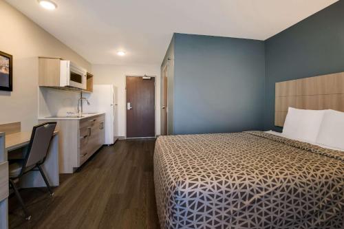 a hotel room with a bed and a desk and a kitchen at WoodSpring Suites Knoxville - Cedar Bluff in Knoxville