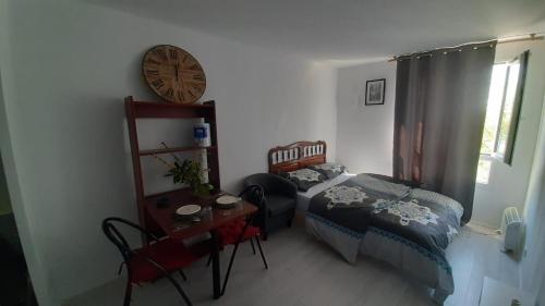 1 dormitorio con 1 cama y reloj en la pared en STUDIO TRES PROPRE de 18 m2, en Cergy