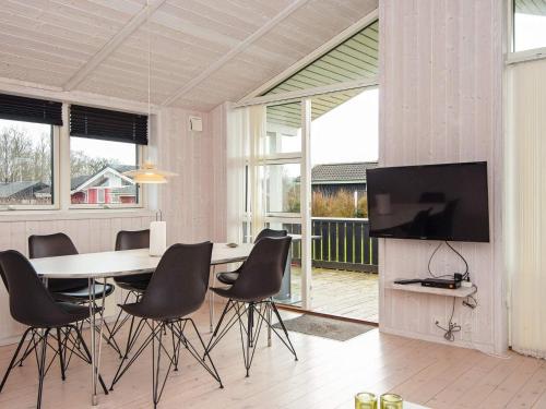 a dining room with a table and chairs and a television at 6 person holiday home in Juelsminde-By Traum in Sønderby