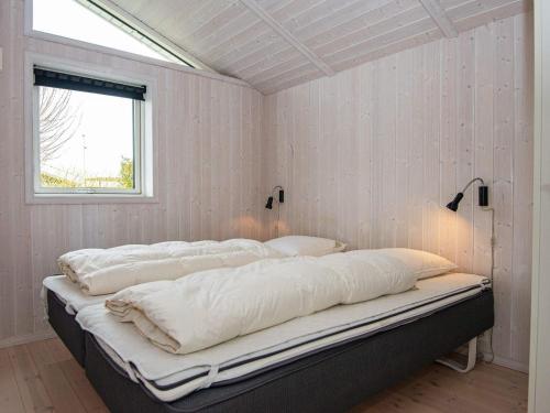 SønderbyにあるThree-Bedroom Holiday home in Juelsminde 18の白い壁と窓が特徴のドミトリールームのベッド1台分です。