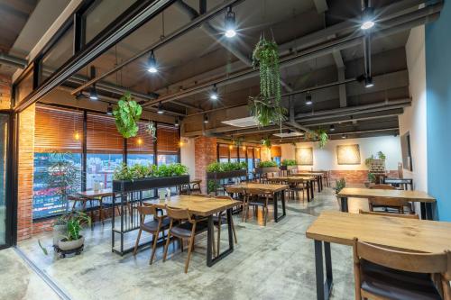 un restaurante con mesas de madera, sillas y plantas en Sorgente Business Hotel, en Busan