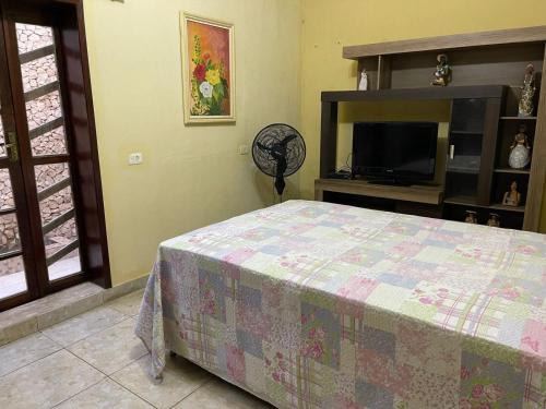 a bedroom with a bed and a flat screen tv at Casa amanhecer in Triunfo