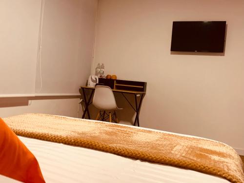 a bedroom with two beds and a desk with a television at CASA CREAZZO 62 - Movistar Arena in Bogotá