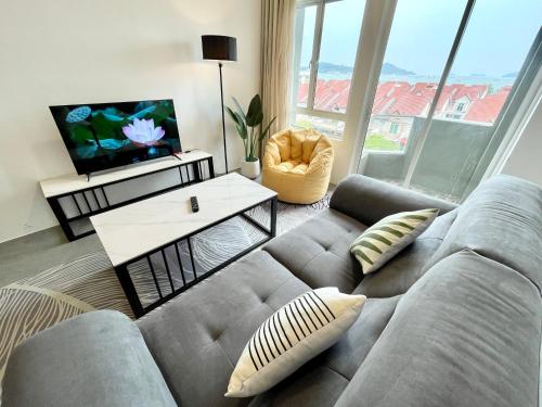 uma sala de estar com um sofá e uma televisão em Langkawi Seaview Cube w/ Rooftop Pool em Kuah
