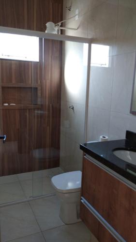 a bathroom with a toilet and a sink and a shower at Casa com piscina - Itapoá in Itapoa