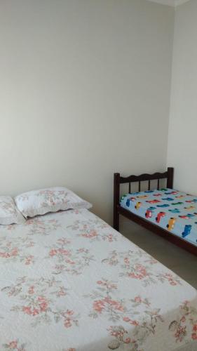 a bedroom with two beds with a bedspread with flowers at Casa com piscina - Itapoá in Itapoa
