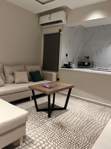sala de estar con mesa y sofá en رواق الضيافة للشقق المخدومة RWAQ Hotel, en Jazan