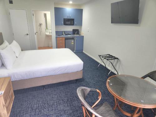 a hotel room with a bed and a table and a desk at Botany Palms Motel in Auckland
