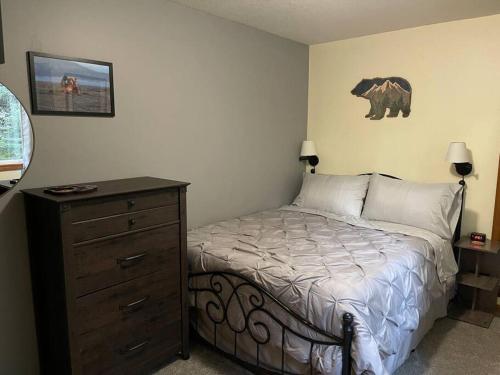a bedroom with a bed with a dresser and a bear on the wall at Den Mishka - Kodiak's Den of the Little Bear in Kodiak