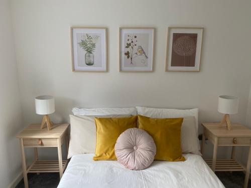 1 dormitorio con 1 cama con almohadas amarillas y 2 mesas en Marine Viewing 2 bedrooms flat en Mánchester