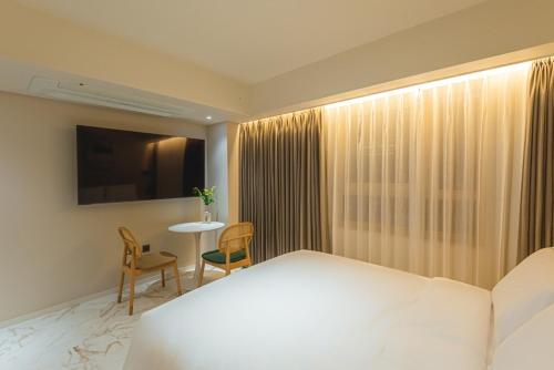 a bedroom with a bed and a table and a television at Asherah Villa d' aqua Hotel in Gimhae