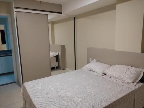 Un dormitorio con una cama grande con sábanas y almohadas blancas. en Apartamento em Ondina, en Salvador