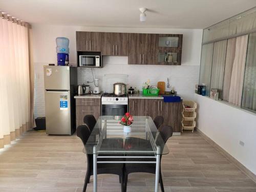 a kitchen with a table with chairs and a refrigerator at Casa de playa con piscina en estreno in Camaná