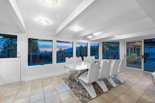 a dining room with white chairs and windows at Seymour Private Bedroom, Ensuite Bathroom with Shared Pool, Hot Tub with Views in North Vancouver