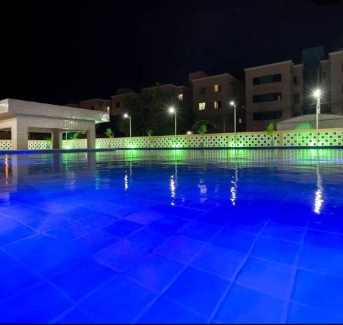 a large swimming pool at night with blue lights at Apartamento Aconchegante em Paulo Afonso in Paulo Afonso