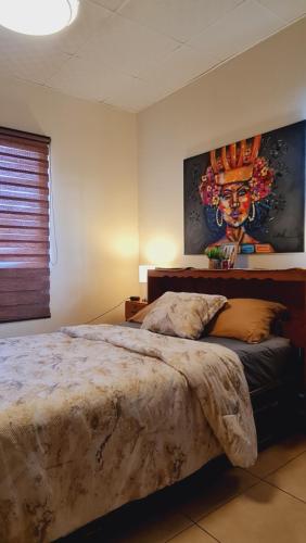 1 dormitorio con 1 cama con una pintura en la pared en Boquete destiny, en Boquete