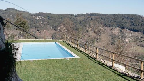 a blue swimming pool on the side of a hill at CASA DO SOL , Turismo Rural in Celorico de Basto