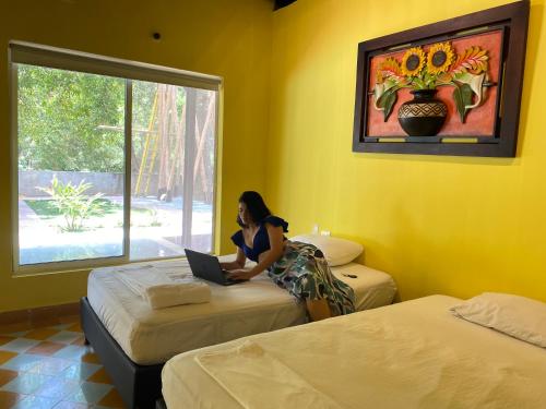 una donna seduta su un letto in una stanza con un portatile di Tayrona Suites a El Zaino