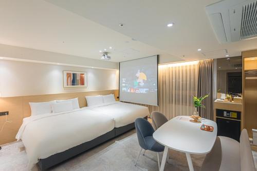 a bedroom with a large white bed and a table and chairs at Asherah Villa d' aqua Hotel in Gimhae