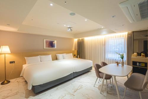 a bedroom with a large white bed and a table at Asherah Villa d' aqua Hotel in Gimhae