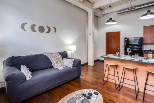 ロチェスターにあるNY Style Centric Loft w/ KingBedの青いソファとキッチンのあるリビングルーム