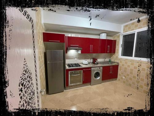 a kitchen with red cabinets and a stove top oven at Standing Tétouan Apparts WIFI&PARKING in Tétouan
