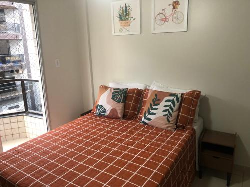 a bedroom with a bed with pillows and a window at A Passos da Areia Apartamento 2 Quartos no Coração da Badalada Praia do Morro - WiFi Fibra in Guarapari