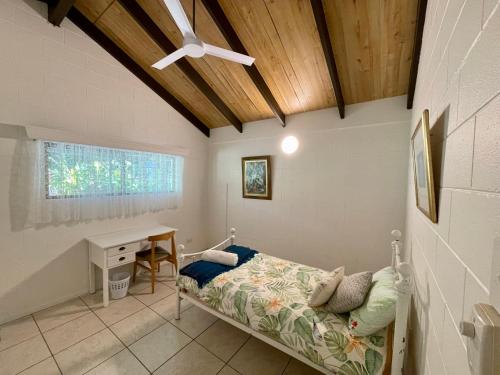 a bedroom with a bed and a desk and a ceiling at Botanica House Kuranda in Kuranda