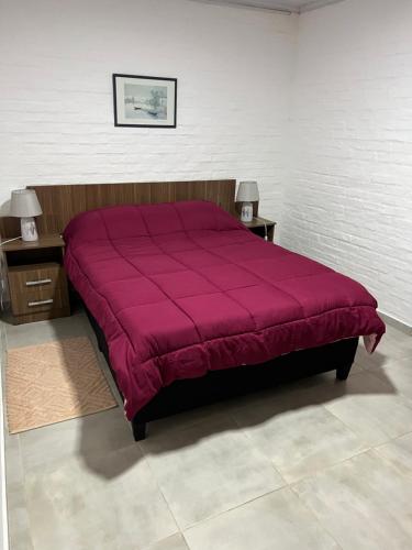 a red bed in a room with two night stands at Apart del Este 5 in Paysandú